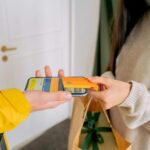 A close-up view of contactless payment transaction using a mobile phone and credit card indoors.